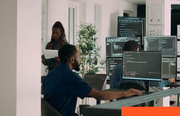 Multiple monitors displaying software code in a technical workspace