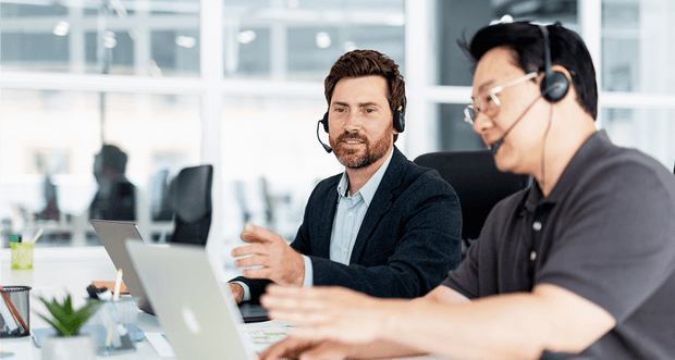 AI Chatbot for Customer Support Two colleagues discussing an AI chatbot for customer support while looking at a laptop