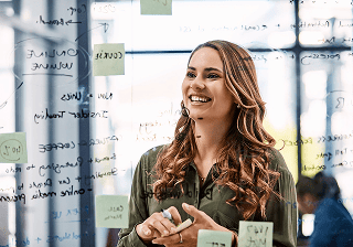 Smiling marketer in front of a whiteboard with sticky notes
