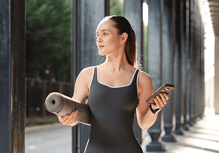 Woman holding a yoga mat and a smartphone